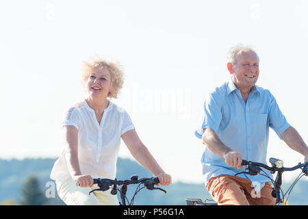 Active elderly couple riding bicycles together in the countryside Stock Photo