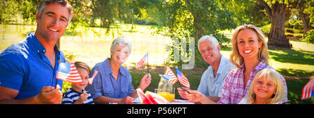 Portrait of family having picnic and holding american flag Stock Photo