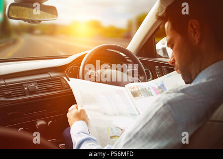 Man sitting in car and looking at road map Stock Photo