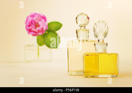 Two vintage bottles of perfume with the glass stoppers and red rose in the empty perfume vial Stock Photo