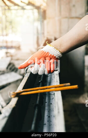Close up of workers hands using pincers bind steel wire to rebar before concrete is poured over it. Stock Photo