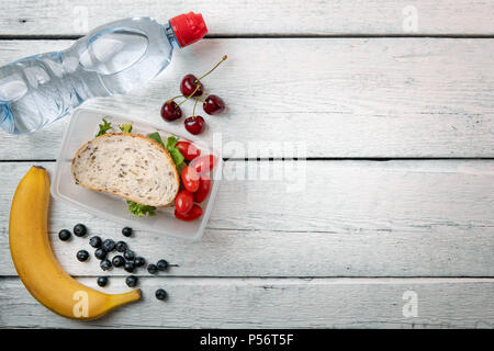 lunch box with sandwich and fruits on white wooden table with copy space Stock Photo