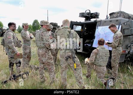 Lance Cpl. Ben Tong, from 1st The Queens Dragoon Guards, part of Battle Group Poland briefs U.K. and U.S. Army soldiers on enemy intel during Saber Strike 18 in Bemowo Piskie Training Area, Poland on June 11, 2018, June 12, 2018. Saber Strike 18 is the eighth iteration of the long-standing U.S. Army Europe-led cooperative training exercise designed to enhance interoperability among allies and regional partners. (Michigan Army National Guard photo by 1st Lt. Erica Mitchell/ released). () Stock Photo