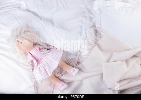 Top view bed with crumpled bed sheet, Good morning after a comfortable sleep. White pillow and blanket. Doll on the bed. Copy space Stock Photo