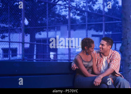 Young Urban ethnic couple flirting on a park bench at dusk or early evening Stock Photo
