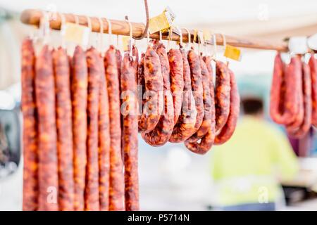 Many chorico sausages hunged on wooden stick at open air market in Portugal Stock Photo