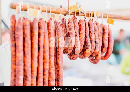 Many chorico sausages hunged on wooden stick at open air market in Portugal Stock Photo