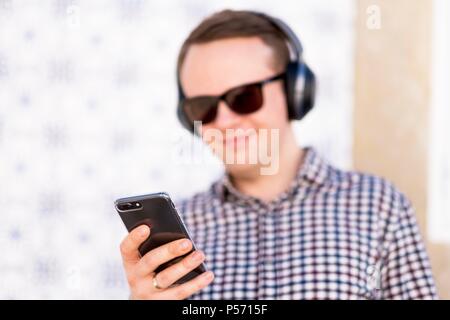 Young man with modern, good quality headphones enjoying the music from his smartphone Stock Photo