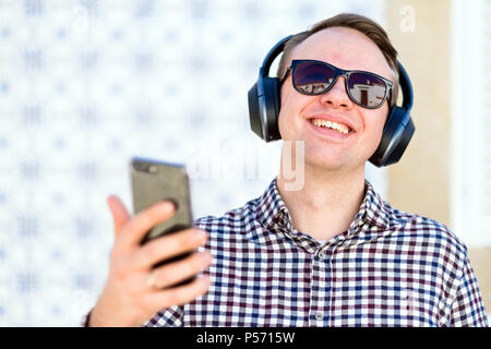 Young man with modern, good quality headphones enjoying the music from his smartphone Stock Photo