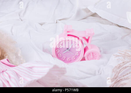 Pink alarm clock and white bed, good morning. Copy space Stock Photo