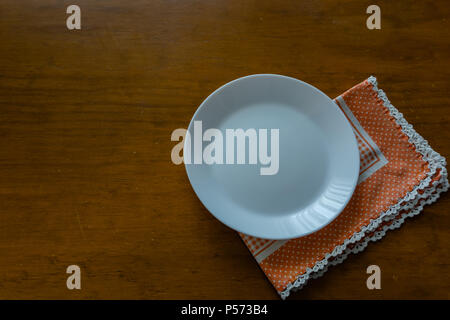 Empty plate on wooden tabletop with tablecloth. Stock Photo