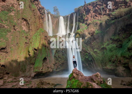 Young woman standing on a stone in front of Ouzoud waterfalls and cascades, Cascades d'Ouzoud, River Oued Tissakht, Middle Atlas Stock Photo