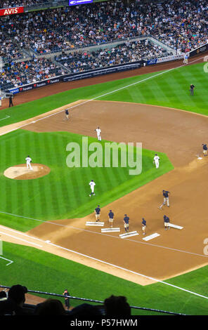 The grounds crew groom the infield dirt between innings during a night game at Yankee Stadium, the Bronx, NYC, USA Stock Photo