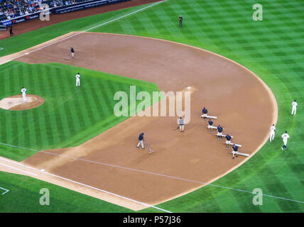 The grounds crew groom the infield dirt between innings during a night game at Yankee Stadium, the Bronx, NYC, USA Stock Photo