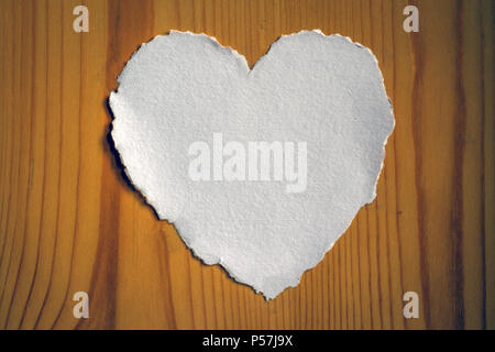 Heart shaped white sheet of paper on a wooden background for love notes Stock Photo