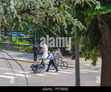 Strasbourg, mature man pushing elderly woman in wheelchair, man cyclist, pedestrian crossing, new-weds, photographer, street, Alsace, Europe Stock Photo