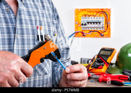 Electrician technician at work with wire stripper on cables in a residential electrical installation. Stock Photo