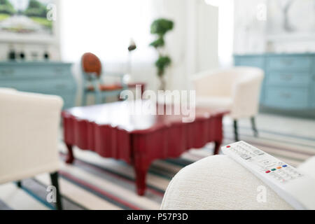 remote control. Program switching or button pressing on TV keypad. Bright living room. Morning european home. Stock Photo
