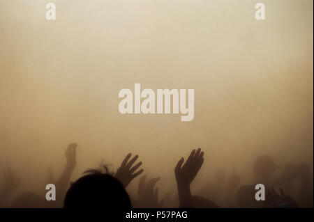 Crowded poeple hands up in the smoke like its a disaster or after a terrorist attack. Stock Photo