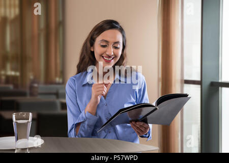 Businesswoman reading magazine on table Stock Photo