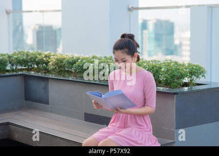 Young Asian executive woman standing and hold folder outside office building, beautiful asian business woman read the document folder outdoor. Stock Photo