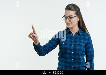 Young woman pointing his finger on abstract light background, touching a digital button on a abstract screen, virtual interface, technology. Stock Photo