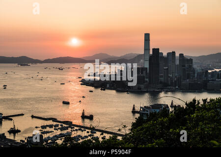 Stunning view of the sunset above the Victoria harbor in Hong Kong with the skyscraper of Kowloon Tsim Sha Tuis waterfront in the left in China Stock Photo