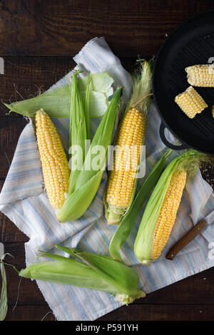 Homemade corn cobs on a dark wooden table, top view Stock Photo