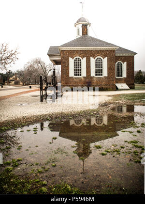 Courthouse in Colonial Williamsburg is reflected in a large pool of melted ice. Stocks are visible. The courthouse is original and built circa 1771. Stock Photo