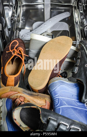 a lot of old shoes loaded in the dishwasher. Misuse of household appliances Stock Photo