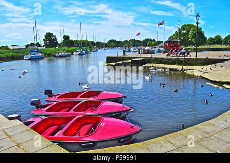 Bright red boats for hire lined up at moorings on the river Stour Estuary at Christchurch Quay,a popular location for sailing boats,yachts & dinghies Stock Photo