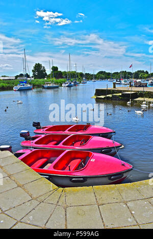 Bright red boats for hire lined up at moorings on the river Stour Estuary at Christchurch Quay,a popular location for sailing boats,yachts & dinghies Stock Photo