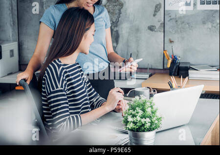 Two asian woman colleagues causal meeting at home office. discuss about business planing at laptop,business teamwork, work mate consulting together Stock Photo
