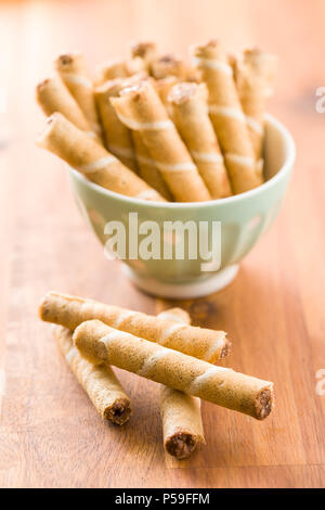 Sweet chocolate waffle rolls on wooden table. Stock Photo