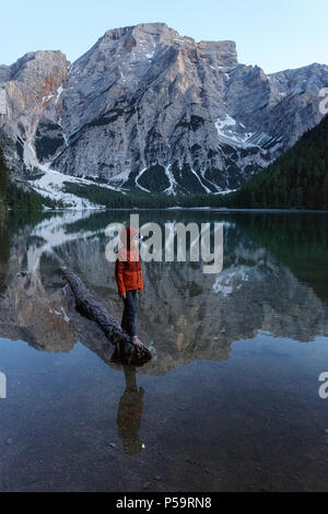 Young boy with a headlamp balancing on sunken log on lake Lago di Braies, Dolomites, Italy. Stock Photo