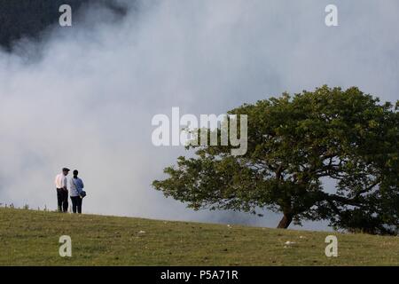 Rheidol valley, Ceredigion, Wales, UK 26th June 2018 UK Weather: People coming to look at a grass fire that has spread along the Rheidol valley near Devils Bridge in Ceredigion, can be seen for miles as thick smoke rises in the air. Fire fighters were called out around 11.30am this morning and are still at the scene. (6.39pm) As the fire is on a steep graded valley, it is making it difficult to extinguish, with the possibility of having to get a helicopter to extinguish it as they are unable to get access. Credit: Ian Jones/Alamy Live News Stock Photo