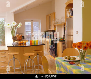 Wood+chrome stools at granite-topped breakfast bar in modern apartment kitchen Stock Photo