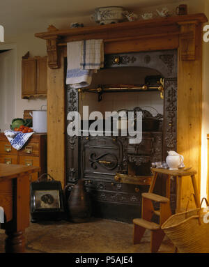 Old wooden step ladder beside Victorian cast iron oven in country kitchen with Victorian coal scuttles Stock Photo