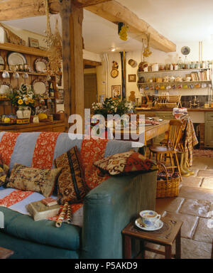Red and blue throw on sofa in open-plan cottage kitchen Stock Photo