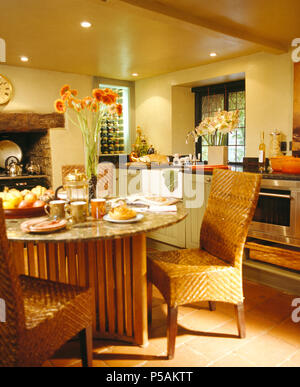 Tall-back woven wicker chairs at granite+wood table  in modern cottage kitchen Stock Photo