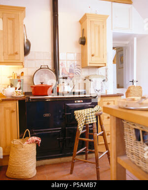 Pine wall cupboards above black Aga in cottage kitchen Stock Photo