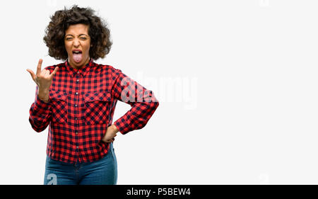 Beautiful arab woman making rock symbol with hands, shouting and celebrating with tongue out Stock Photo