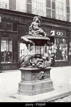 Fontaine No. 1 Rue du Fbg. [i.e. Faubourg] St Martin (fonte). No. 16. English: Cast iron fountain on curb of city street, plinth supportingmale figures with fish tails supporting bowl holding a child figure with shells. Inscription on plinth. Shop front in background. circa 1865. N/A 327 Charles Marville, Fontaine No. 1 Rue du Faubourg-Saint-Martin, ca. 1865 Stock Photo