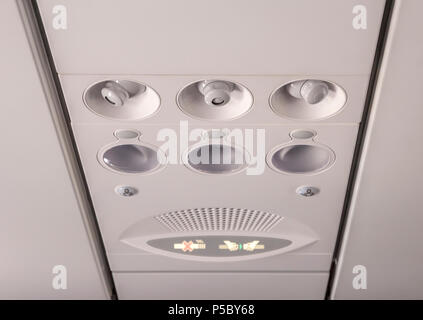 Adjustable lights and air conditioners overhead seat controls of a commercial aircraft in an airplane with no-smoking and seat belt on signs Stock Photo