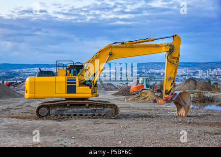 Evening, yellow excavator with shovel  at construction site Stock Photo