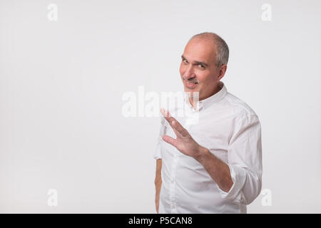 Mature hispanic man in white shirt showing a gesture like stop please, it is enough. Stock Photo