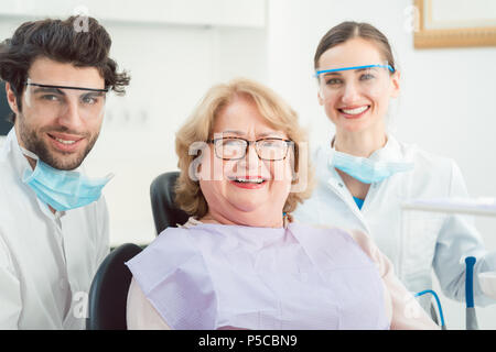 Dentists and patient in surgery looking at camera Stock Photo