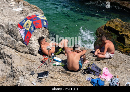 Men sunbathing on rocks at Ras Beirut beside The Corniche in Beirut, Lebanon. Stock Photo