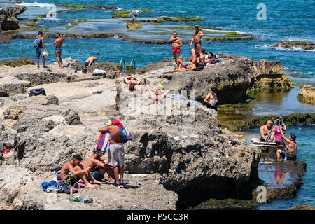 Men sunbathing on rocks at Ras Beirut beside The Corniche in Beirut, Lebanon. Stock Photo