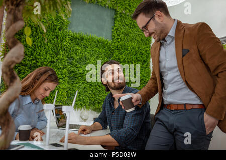 Smart qualified skilled young engineers looking at the project of alternative energy with miniatures of windmill turbines at the table. Stock Photo
